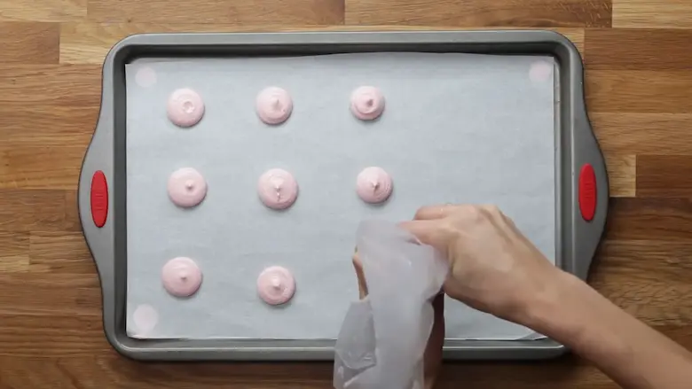 Preparing Macarons on a baking tray with a piping bag