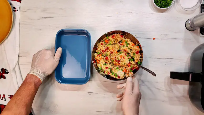 adding mixed veggies and rice into the baking dish - Air Fryer Fried Rice